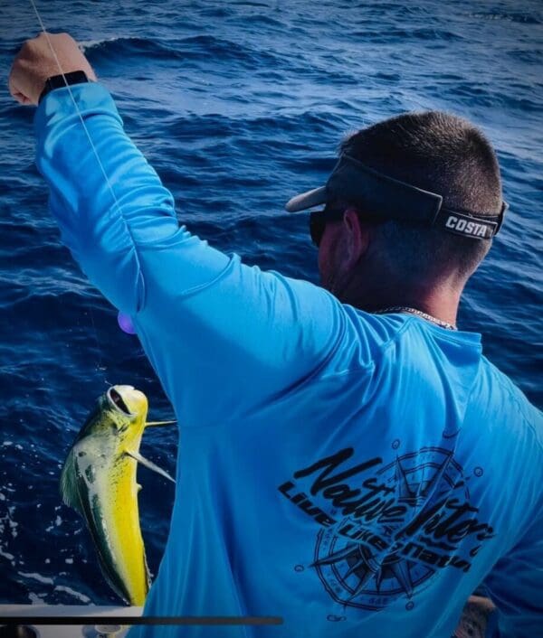 A man holding onto a yellow fish while standing in the ocean.