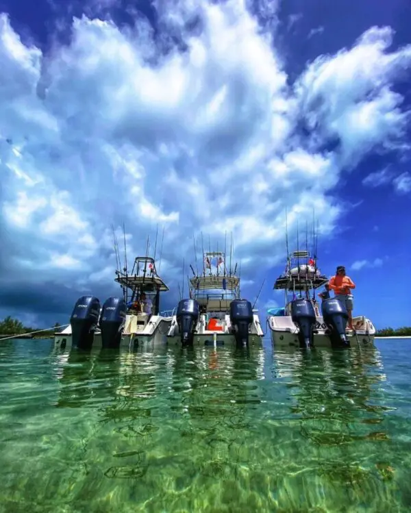 A group of boats in the water under a cloudy sky.