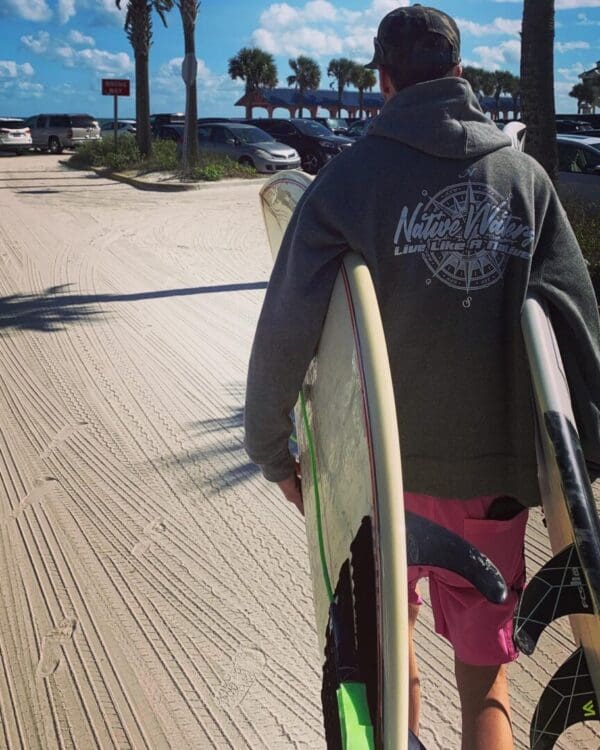 A man walking down the street with his surfboard.